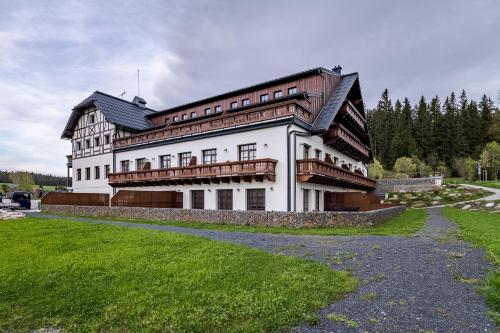 a large white building with a gambrel roof at Wellness apartmán Pila Kvilda in Kvilda