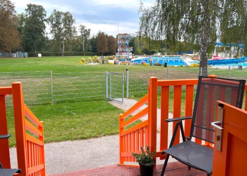 ゲッティンゲンにあるFerienhauspark im Freibad Brauweg - Rolling Lodgesの公園のデッキにある2つのオレンジ色のベンチ