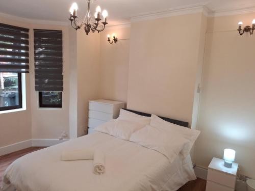 Un dormitorio con una cama con sábanas blancas y una lámpara de araña. en Peacock Quarters, en Croydon
