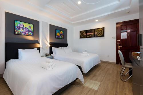 a hotel room with two beds with white sheets at Luxury Hotel Saigon in Ho Chi Minh City