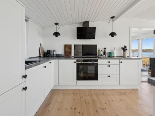 Il comprend une cuisine blanche avec des placards blancs et du parquet. dans l'établissement Holiday Home Solbritt - 30m from the sea by Interhome, à Broager