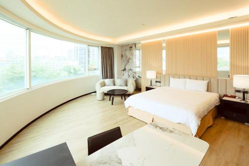 a hotel room with a bed and a chair at Herkang Hotel in Taichung