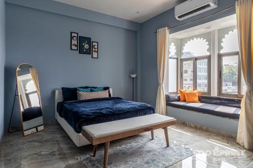 a bedroom with blue walls and a bed and a bench at Footprint By The Lake in Udaipur