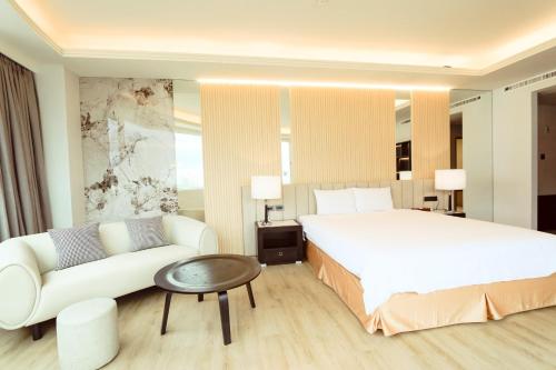 a bedroom with a large white bed and a couch at Herkang Hotel in Taichung