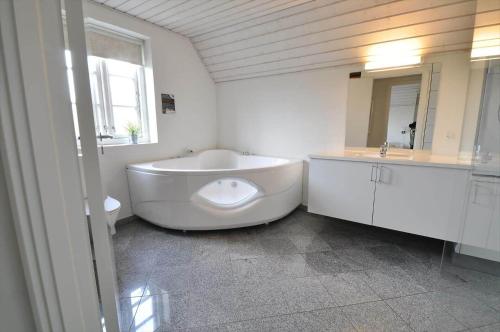 a white bathroom with a large tub and a sink at 10849-Ulfborg-Dommersovej-17 in Øby