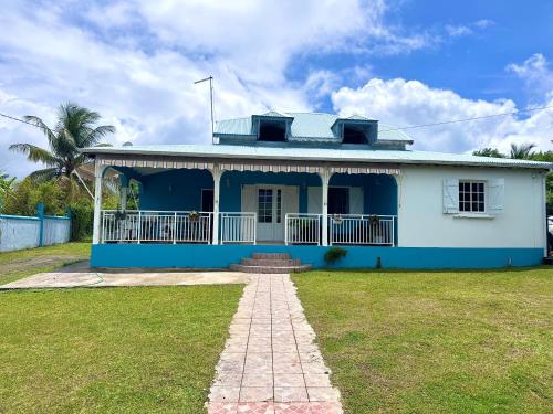 a blue and white house with a grass yard at Ameli'ber in Sainte-Rose