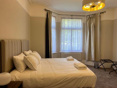 a bedroom with a bed with white sheets and a window at 4-Bedroom Apartment – Sleeps 7 – Paddington – Quiet Area in London
