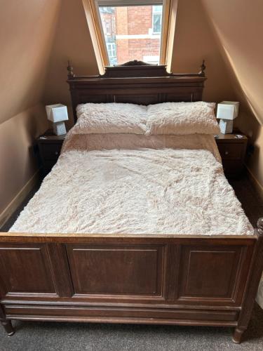 a large wooden bed in a bedroom with a window at Keepers Lodge in Nottingham