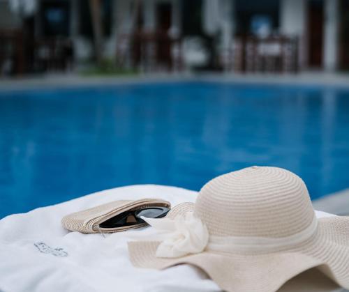 a white straw hat and sunglasses sitting next to a swimming pool at Rio Cumbaza Hotel in Tarapoto