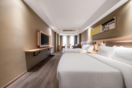 杭州市にあるShengfeng Mingzuo Hotelのベッド2台とテレビがあるホテルの部屋