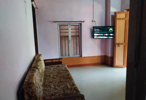 a couch sitting in a room with a window at Gawade Niwas in Corgao