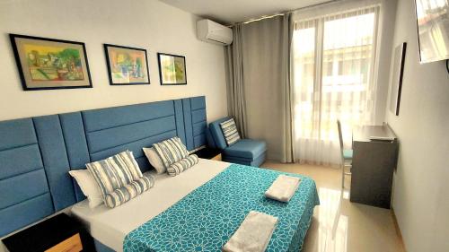 a bedroom with a blue and white bed and a chair at Luxury Lighthouse Golf Villa in Balchik
