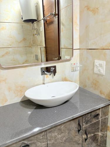 a bathroom with a white sink and a mirror at The Nuvon Residency CR Park in New Delhi