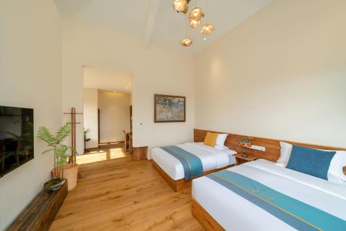 a hotel room with two beds and a television at Floral Hotel Tengchong Wuwenju B&B in Tengchong