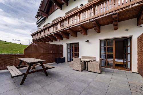 a patio with a table and chairs and a wooden balcony at Wellness apartmán Pila Kvilda in Kvilda