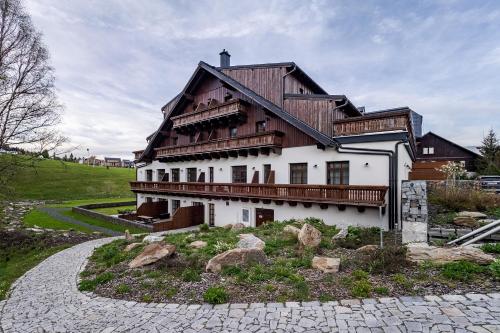 a house with a wooden roof on a hill at Wellness apartmán Pila Kvilda in Kvilda