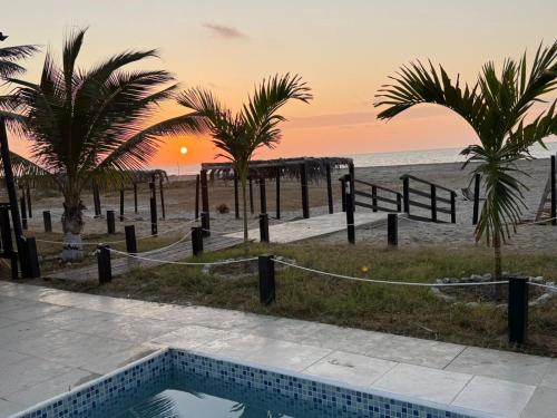 a swimming pool next to a beach with palm trees at Las cabañas de Bonanza in Zorritos