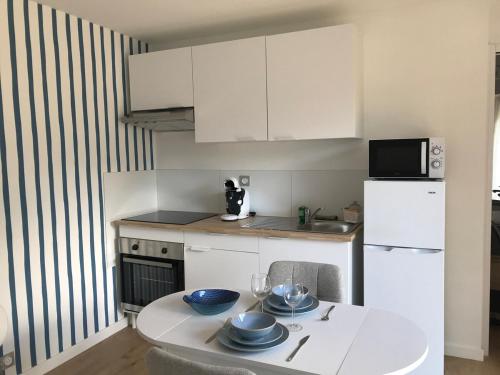 ラ・テュルバルにあるLoft en bois avec terrasse et jardin à La Turballeのキッチン(白いテーブル、白い冷蔵庫付)