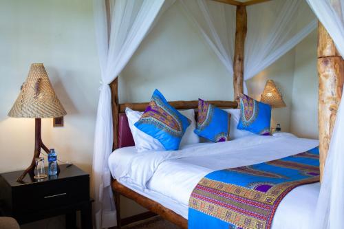 a bedroom with a canopy bed with blue pillows at Saba House and Lodges in Machakos