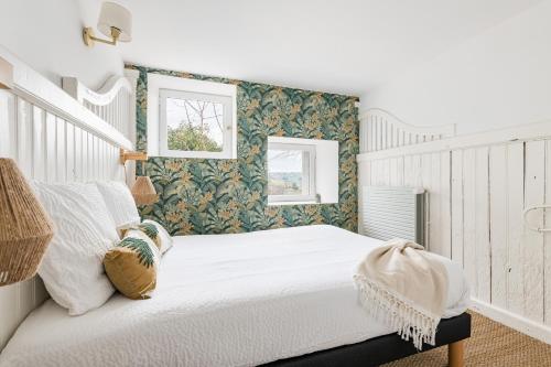 a bedroom with a white bed with green and white wallpaper at Appartement T2 dans des anciennes écuries in Saint-Galmier