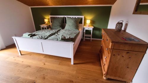 a bedroom with a white bed and a wooden dresser at Ferienhaus Fringaluna in Übersee