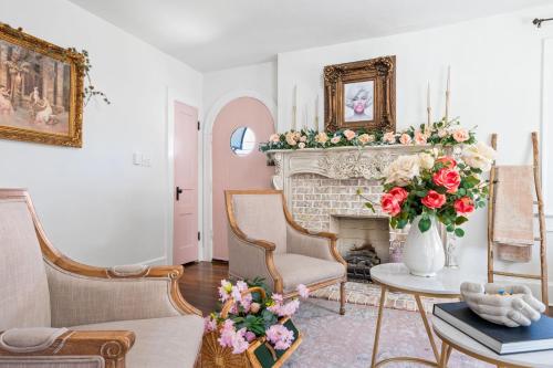 a living room with a fireplace with a vase of roses at The Pink and Old Clarksville House - Alpha Link Homes in Clarksville
