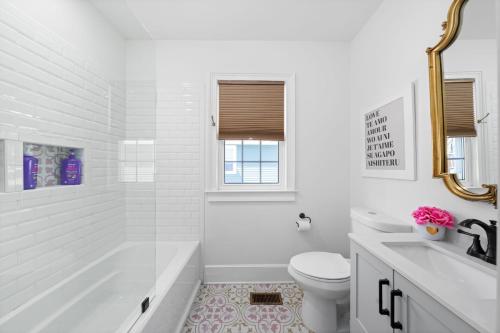 a white bathroom with a tub and a toilet and a sink at The Pink and Old Clarksville House - Alpha Link Homes in Clarksville