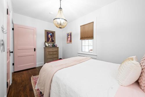 a bedroom with a white bed and a chandelier at The Pink and Old Clarksville House - Alpha Link Homes in Clarksville