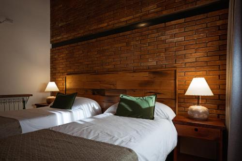 two beds in a room with a brick wall at Valle Andino in Uspallata