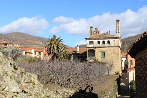 an old building in a town with mountains in the background at Apartamentos Rurales La Lancha in Aldeanueva de la Vera
