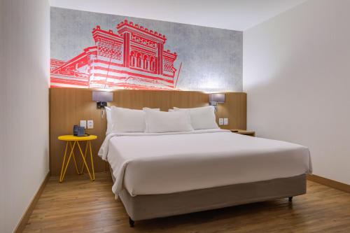 a bedroom with a large bed and a painting on the wall at Radisson RED Campinas in Campinas
