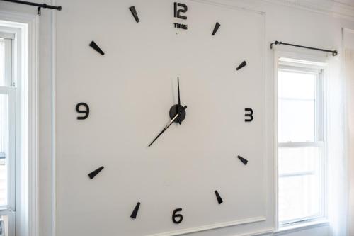 a clock on a wall next to two windows at "Bayonne Escape, Free Parking & NYC Nearby" in Bayonne