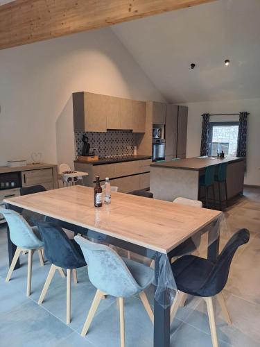 a large wooden table in a kitchen with blue chairs at Au pied de La Redoute in Sougné-Remouchamps