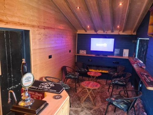 a bar with chairs and a tv in a room at Upper Eyton Farmhouse B&B in Shrewsbury