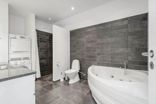 a bathroom with a tub and a toilet and a sink at 70774-Ulfborg-Skolegade-15-Lejl-5 in Thorsminde