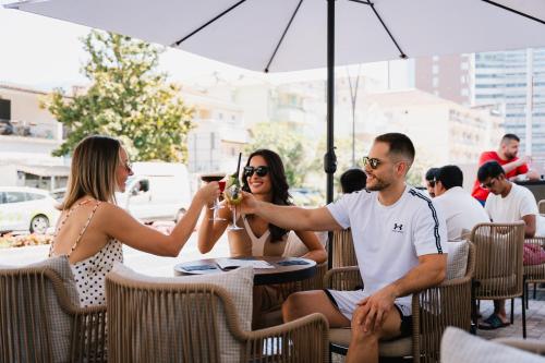 a man taking a picture of two women sitting at a table at Kondo Hotel Allure in Budva