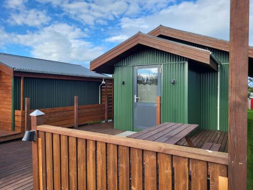 a green building on a deck with a wooden fence at Vonarland in Stokkseyri