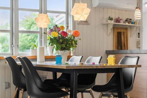 a dining room table with chairs and a vase of flowers at 30185-Ulfborg-Bellisvej-509 in Vang
