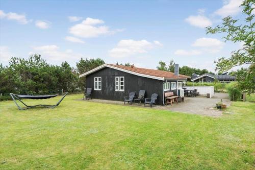 a small black house with a hammock in a yard at 30185-Ulfborg-Bellisvej-509 in Vang