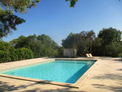 a swimming pool in a yard with trees in the background at Le mazet d'Uzès in Uzès