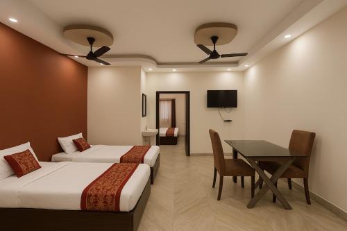 a room with two beds and a table and a television at Kasba Jahaaz Kali Ghat Home Stay in Kolkata