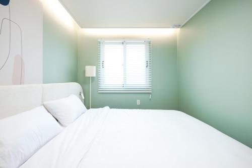 a white bed in a room with a window at Busan Jeonpo Station 3min Rooftop Stay in Samgong