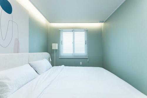 a bedroom with a white bed and a window at Busan Jeonpo Station 3min Rooftop Stay in Samgong