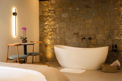 a bathtub in a bedroom with a stone wall at Naatooh Guest Houses in Florianópolis