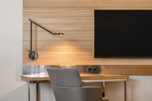 a desk with a television on a wall with a chair at Novotel München City in Munich