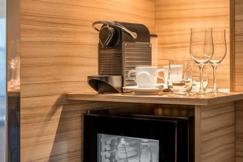 a table with wine glasses and a coffee maker at Novotel München City in Munich
