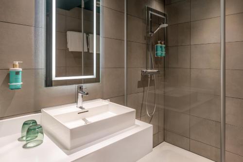 a bathroom with a white sink and a shower at Novotel München City in Munich