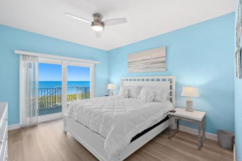 1 dormitorio azul con 1 cama y balcón en Versailles Sur La Mer 1D, en Melbourne Beach