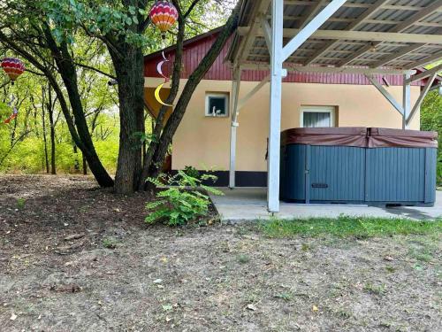 a house with a blue garage next to a tree at Varázslakos Tanya in Soltvadkert