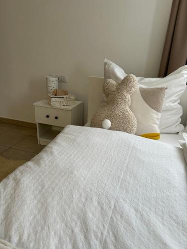 a white bed with two stuffed animals on it at Varázslakos Tanya in Soltvadkert